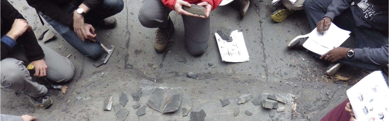 Students discuss rock fragments and take notes.